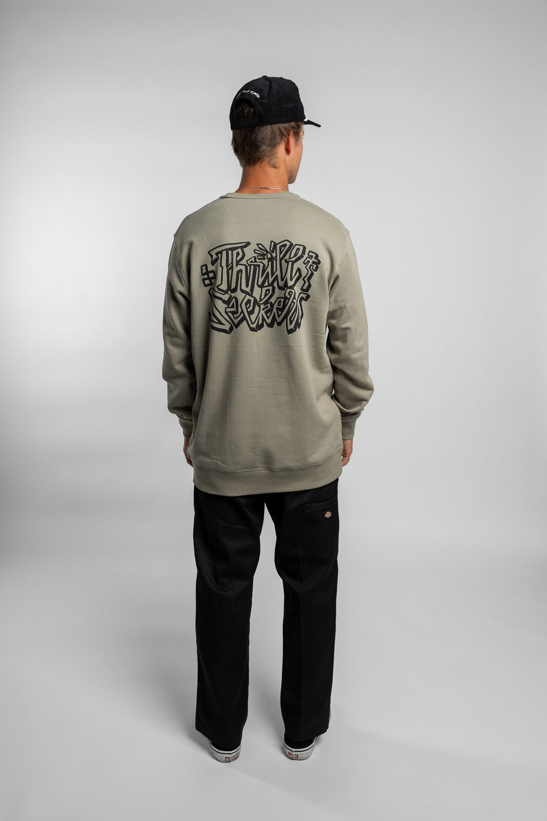 Person wearing eucalyptus crewneck with 'Thrill Seekers' scribe logo