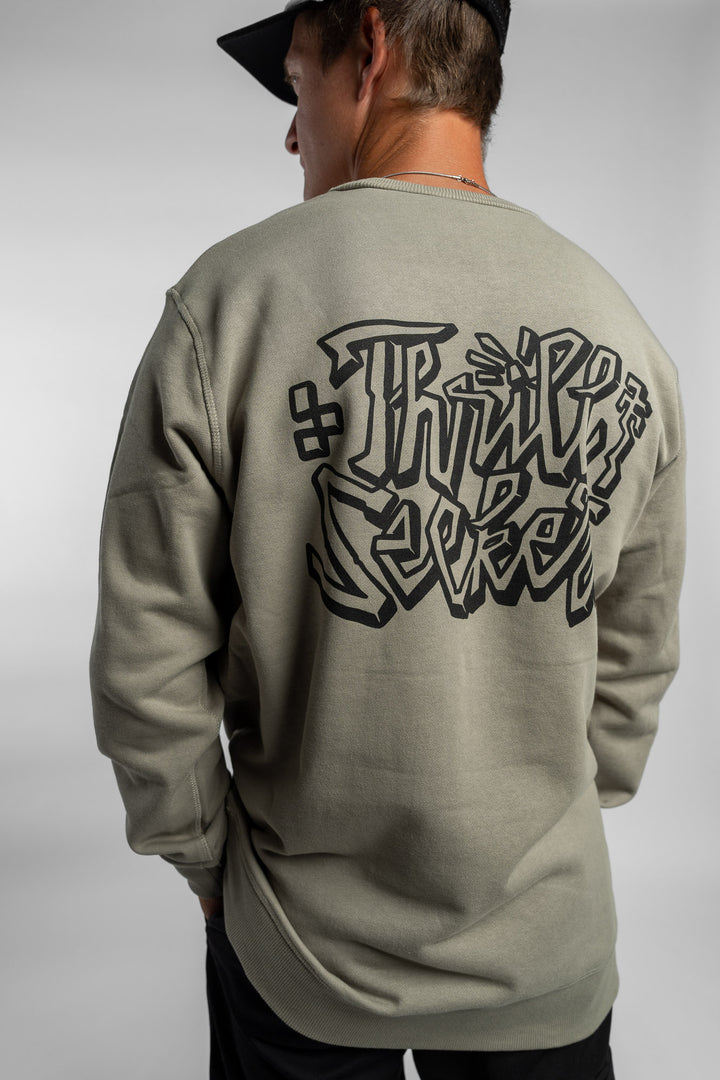 Person wearing eucalyptus crewneck with 'Thrill Seekers' scribe logo