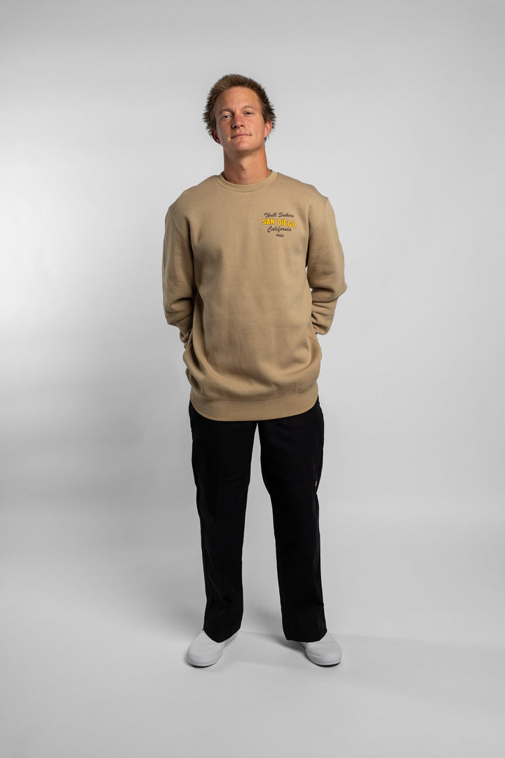 Person wearing sand crewneck with 'Thrill Seekers' shop logo