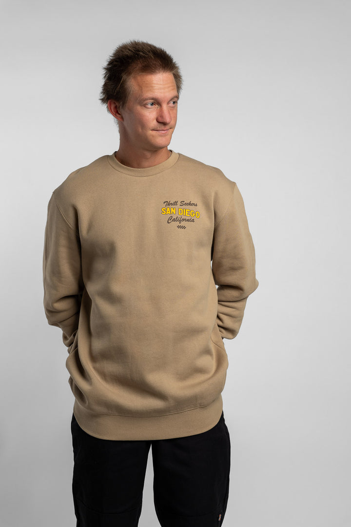 Person wearing sand crewneck with 'Thrill Seekers' shop logo