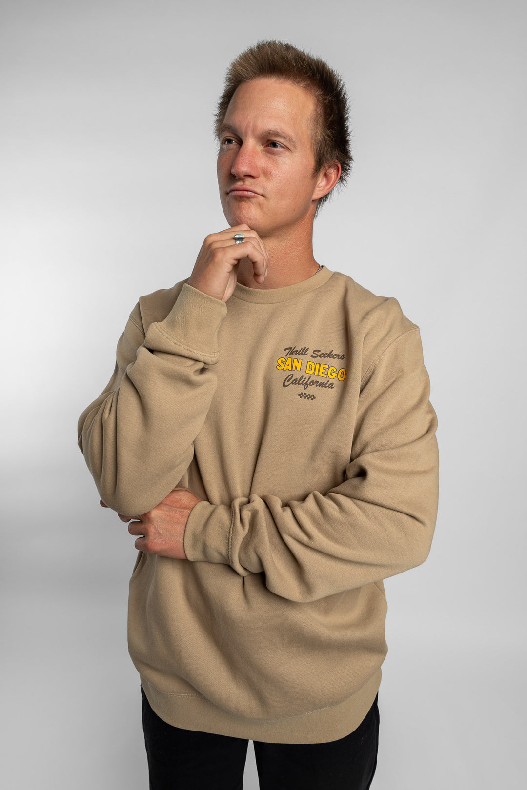 Person wearing sand crewneck with 'Thrill Seekers' shop logo
