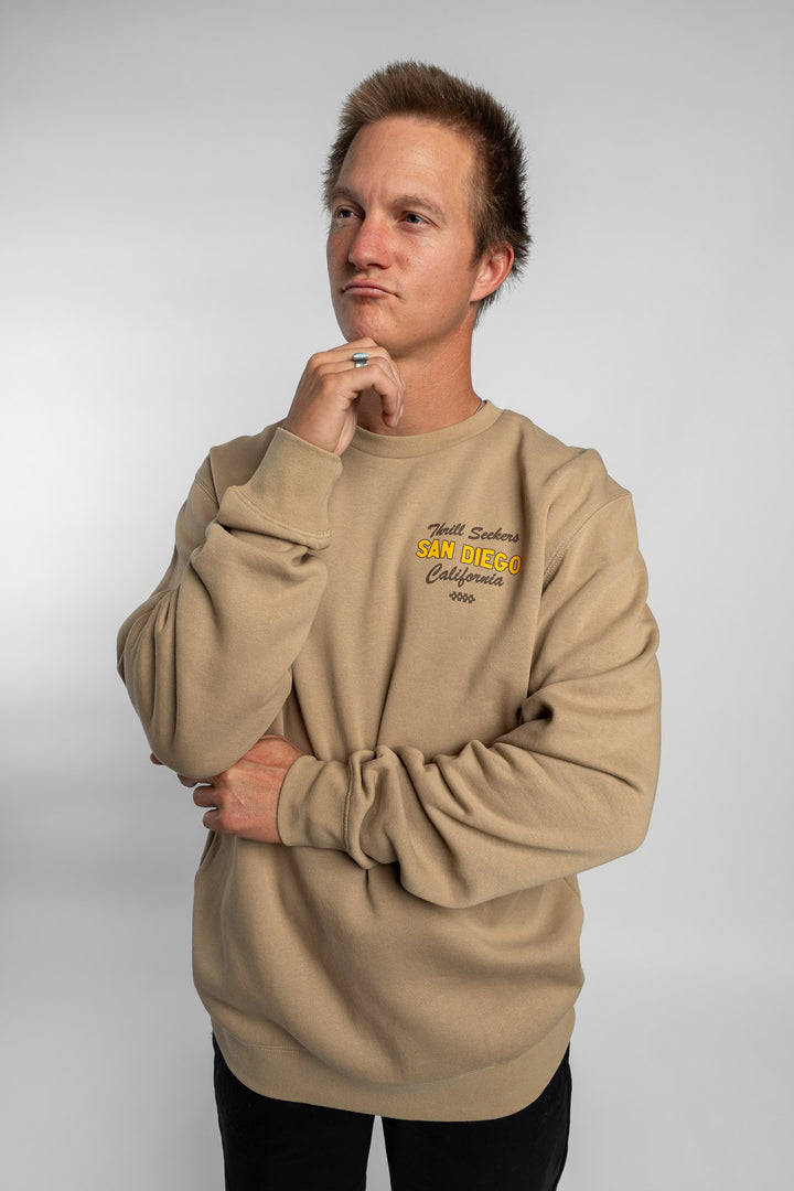 Person wearing sand crewneck with 'Thrill Seekers' shop logo
