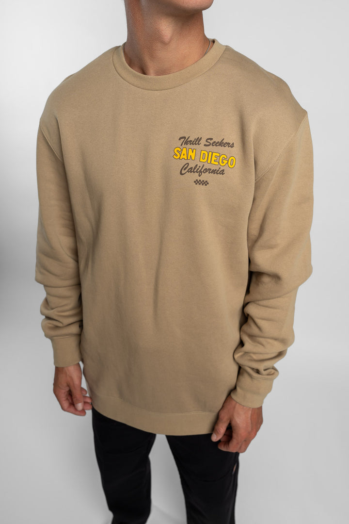 Person wearing sand crewneck with 'Thrill Seekers' shop logo