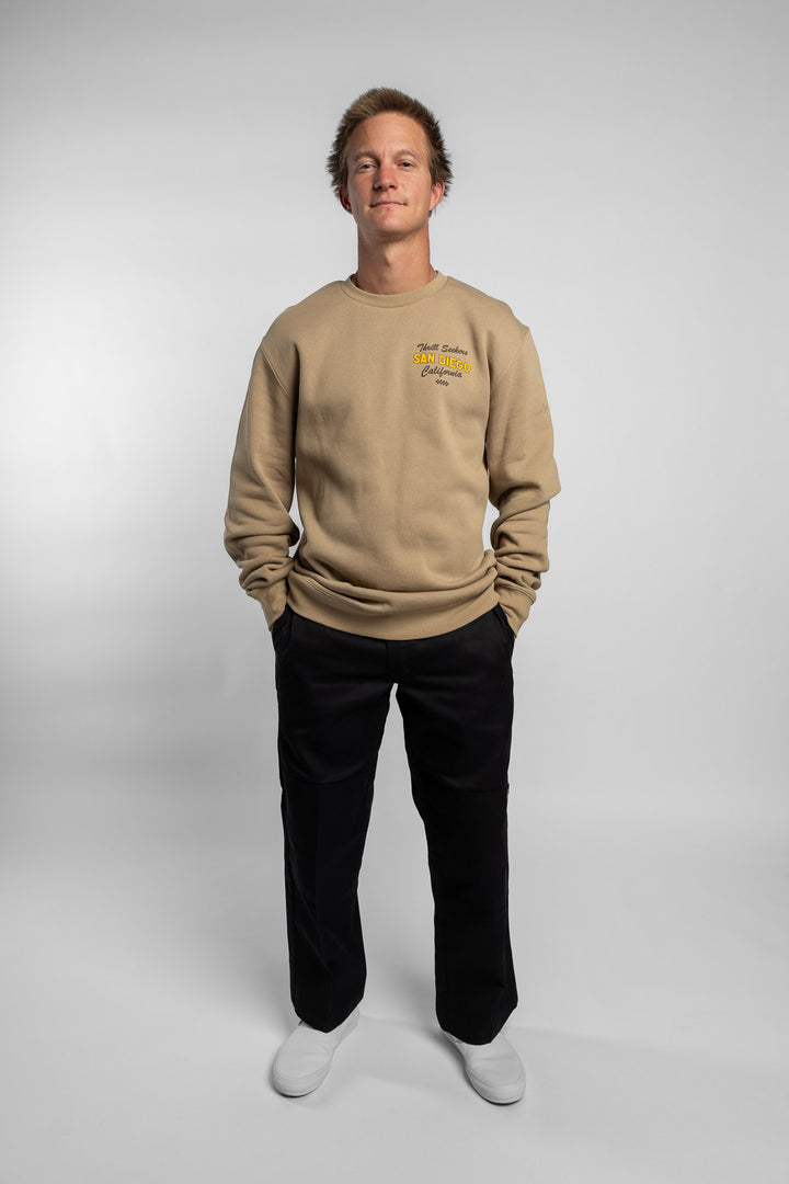 Person wearing sand crewneck with 'Thrill Seekers' shop logo