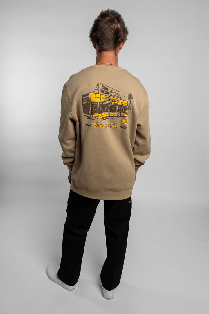 Person wearing sand crewneck with 'Thrill Seekers' shop logo