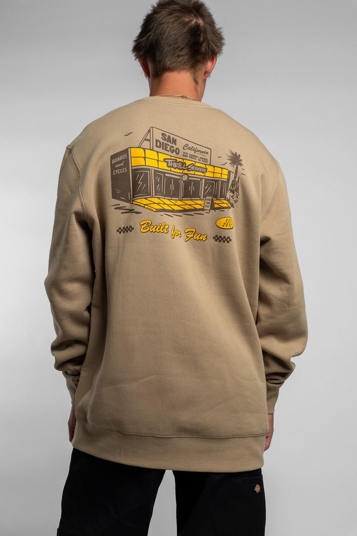 Person wearing sand crewneck with 'Thrill Seekers' shop logo