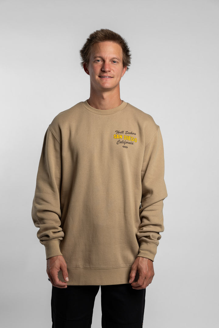 Person wearing sand crewneck with 'Thrill Seekers' shop logo
