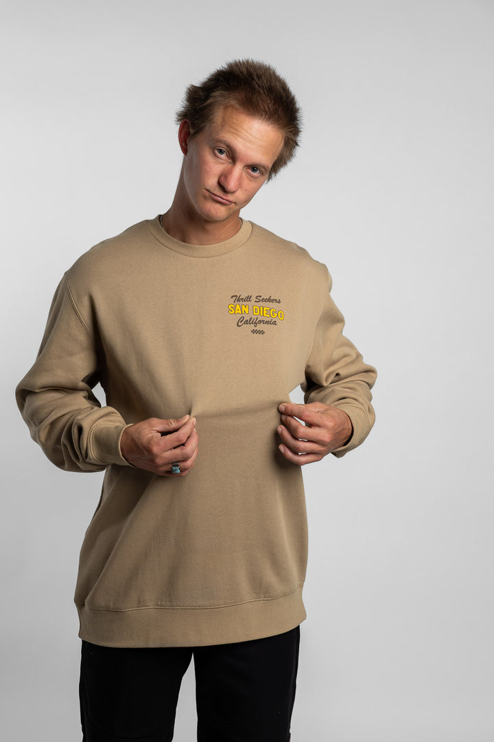 Person wearing sand crewneck with 'Thrill Seekers' shop logo