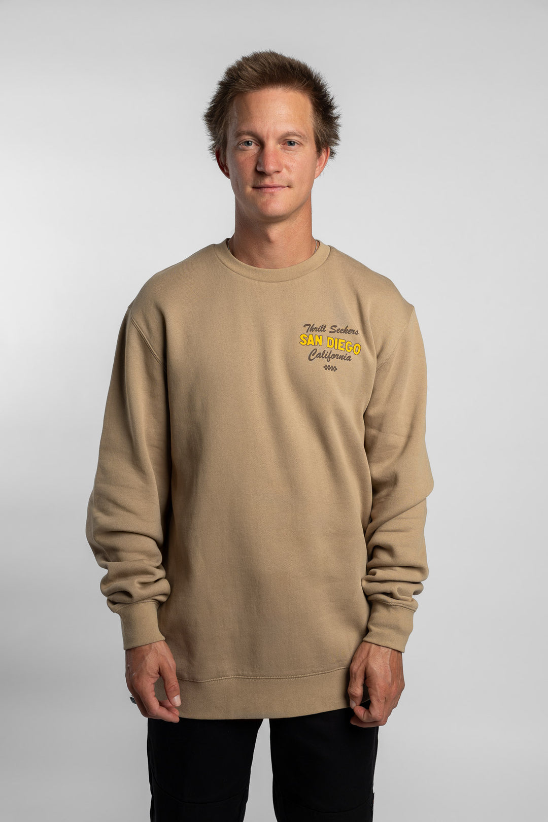 Person wearing sand crewneck with 'Thrill Seekers' shop logo