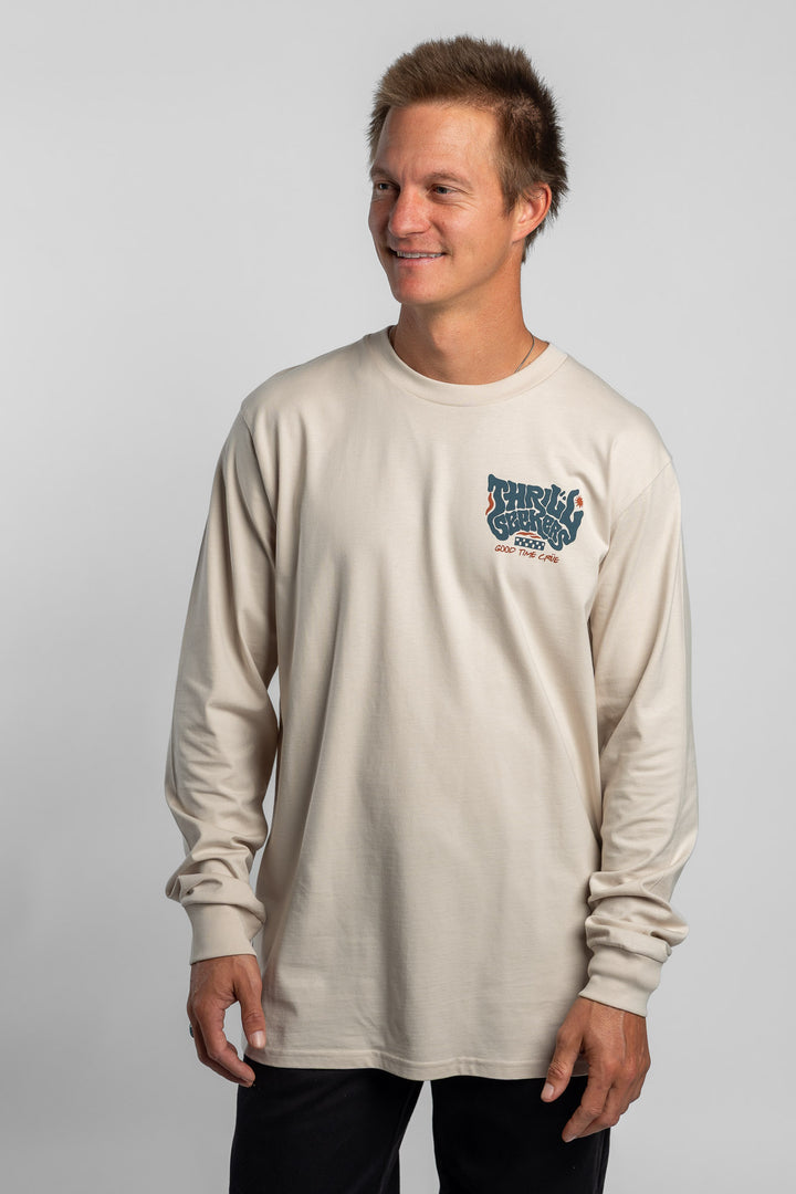 Person wearing a bone colored long-sleeve shirt with a 'Thrill Seekers' logo