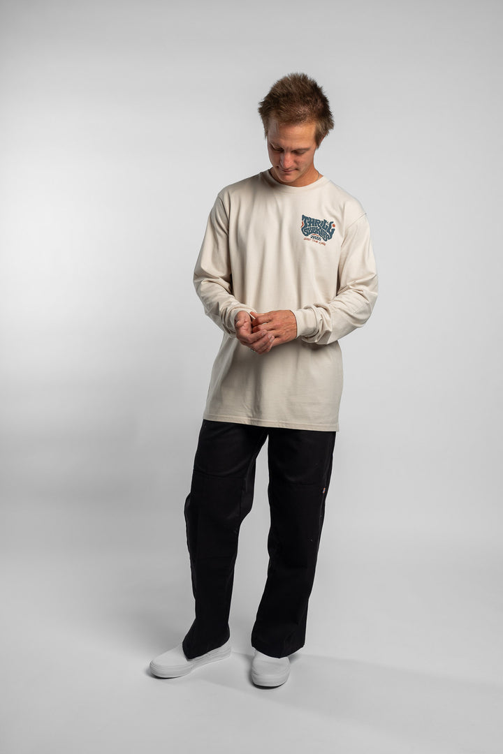 Person wearing a bone colored long-sleeve shirt with a 'Thrill Seekers' logo