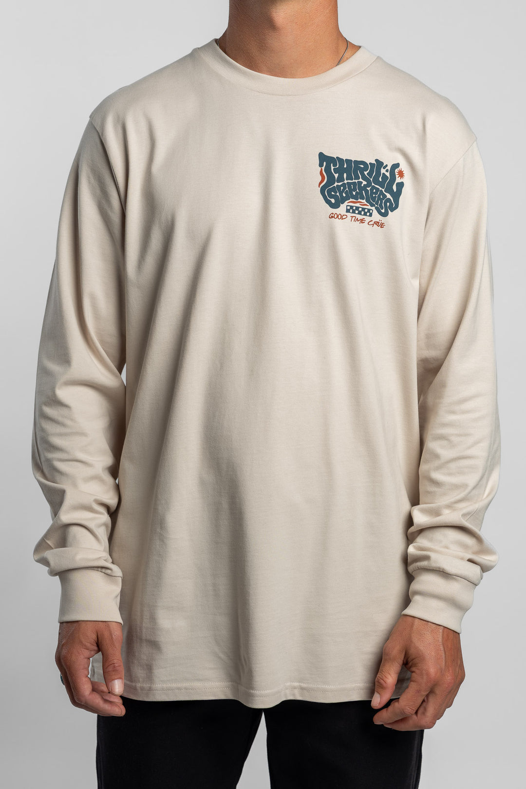 Person wearing a bone colored long-sleeve shirt with a 'Thrill Seekers' logo