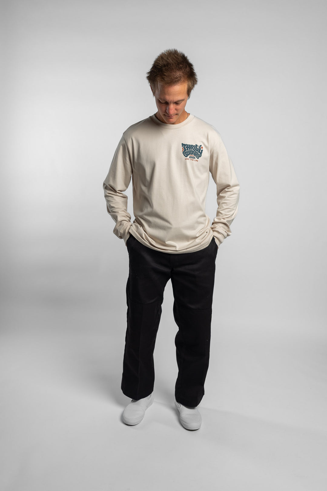 Person wearing a bone colored long-sleeve shirt with a 'Thrill Seekers' logo