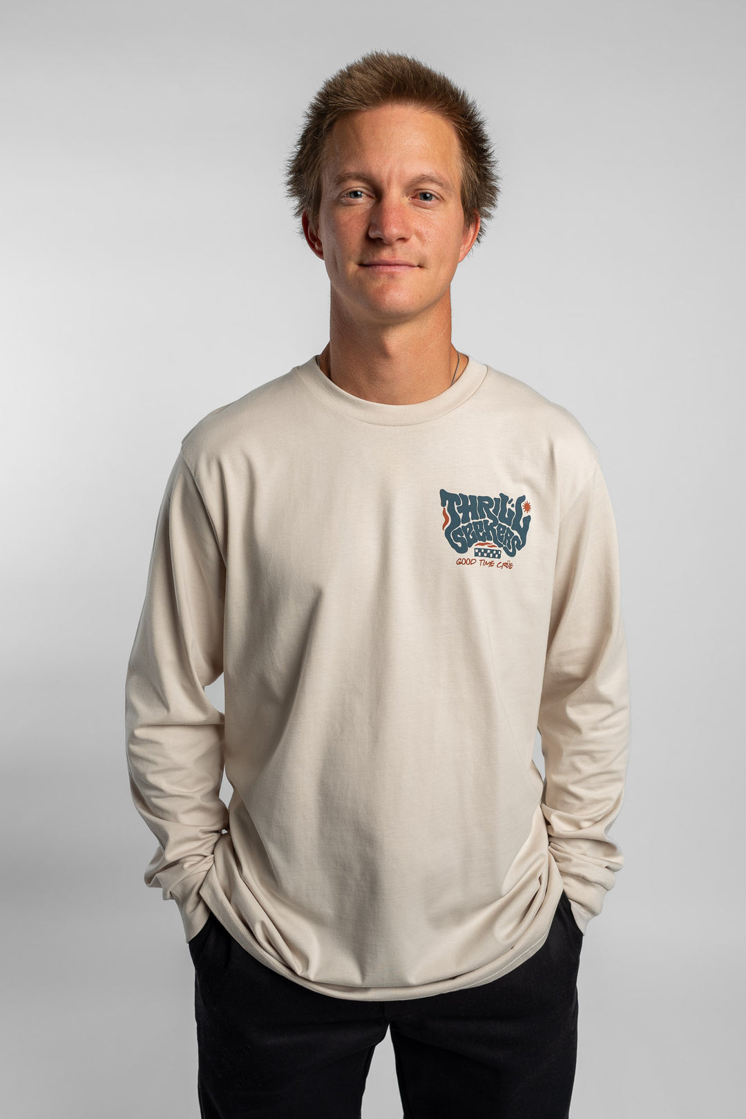 Person wearing a bone colored long-sleeve shirt with a 'Thrill Seekers' logo
