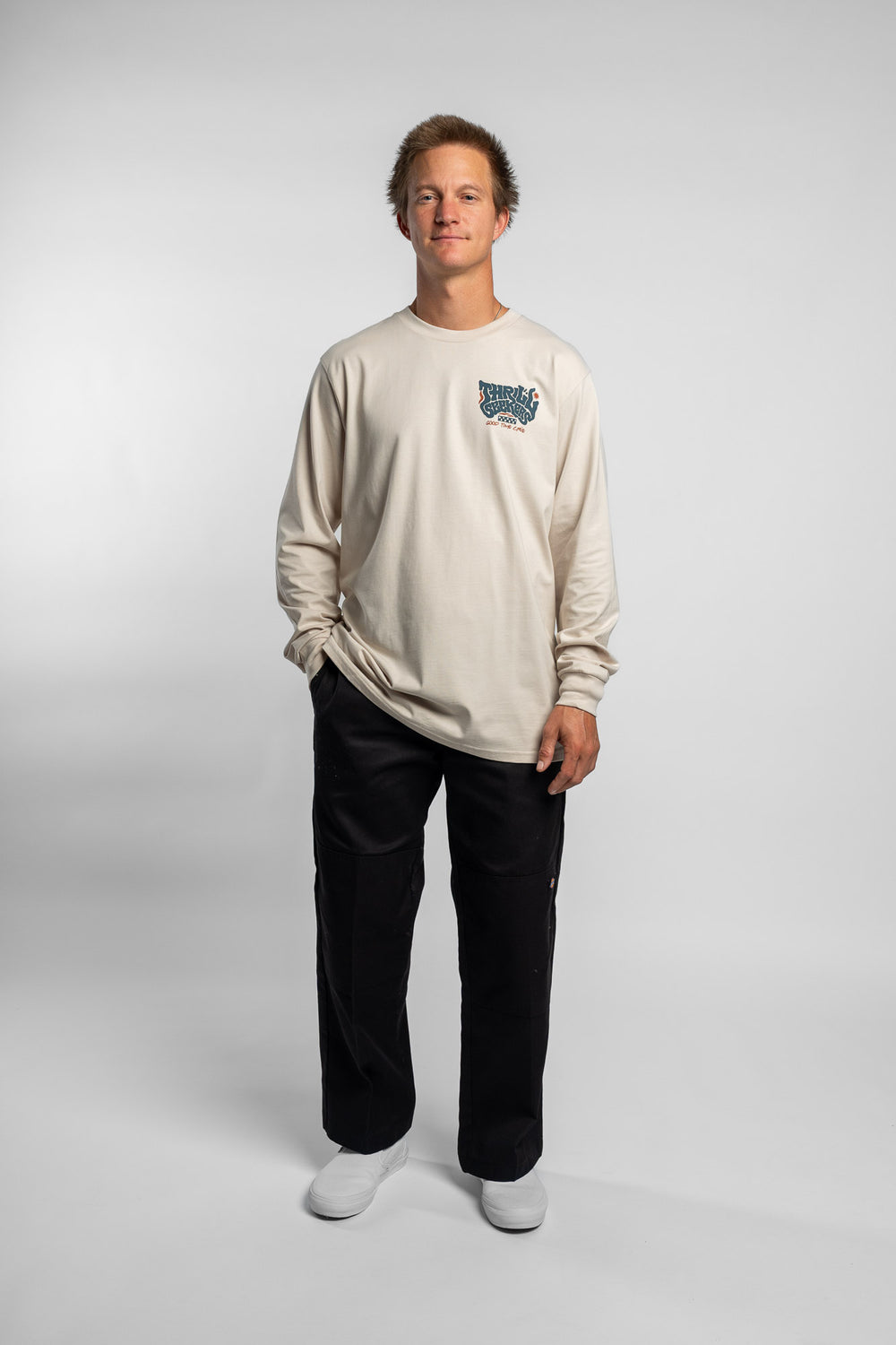 Person wearing a bone colored long-sleeve shirt with a 'Thrill Seekers' logo