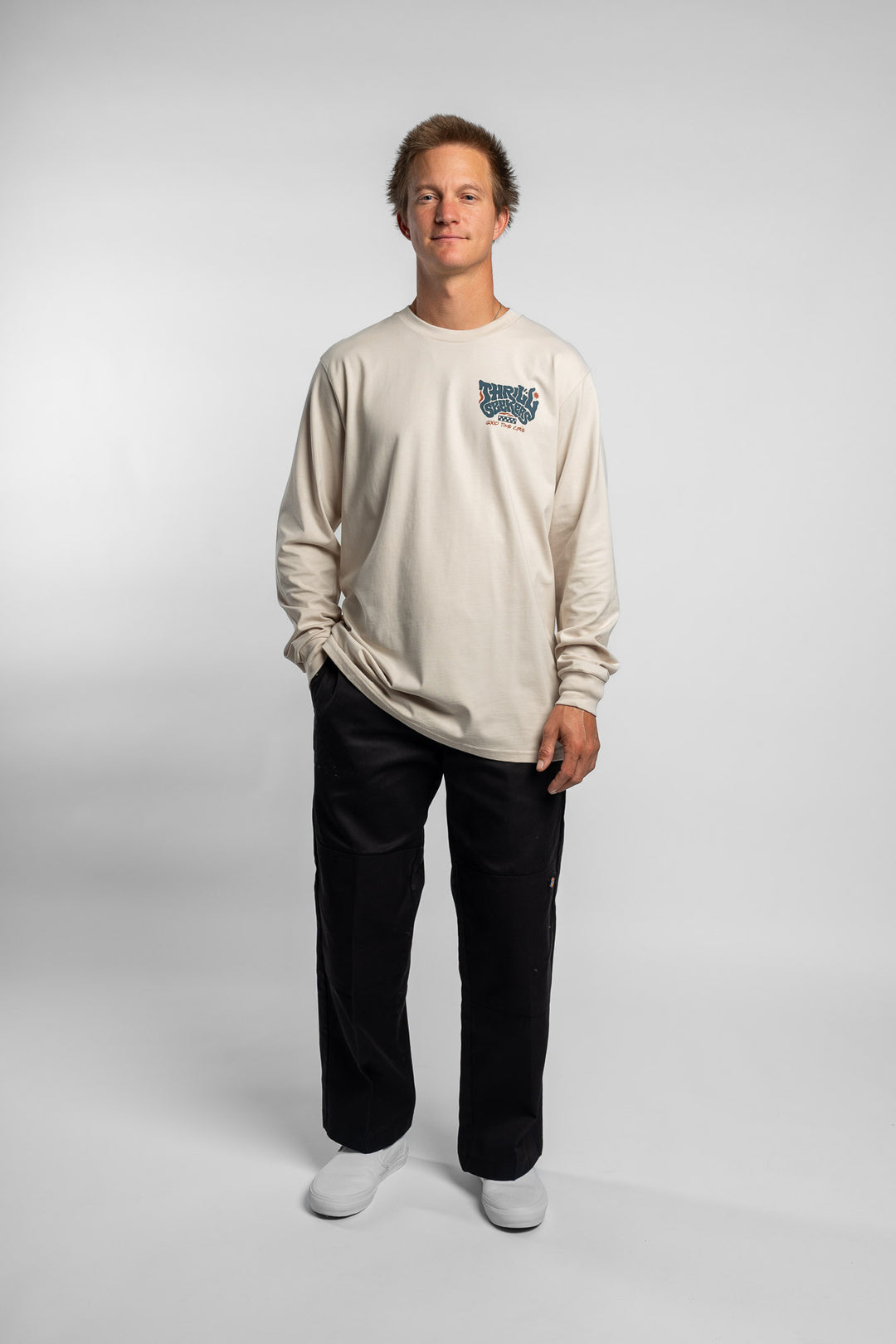 Person wearing a bone colored long-sleeve shirt with a 'Thrill Seekers' logo