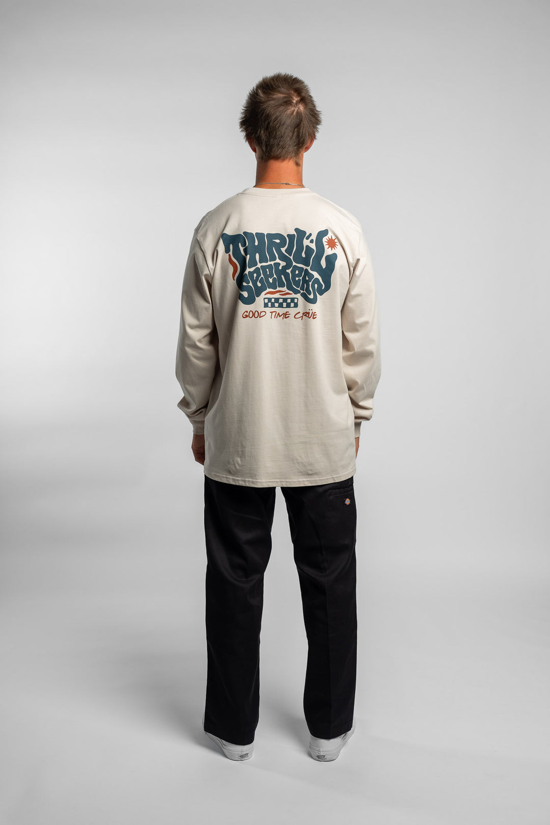 Person wearing a bone colored long-sleeve shirt with a 'Thrill Seekers' logo