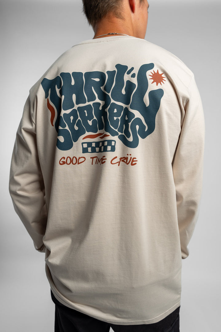 Person wearing a bone colored long-sleeve shirt with a 'Thrill Seekers' logo