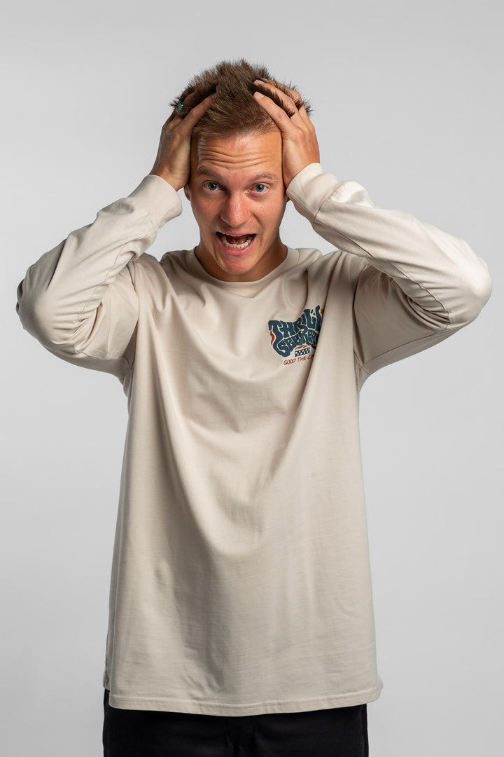 Person wearing a bone colored long-sleeve shirt with a 'Thrill Seekers' logo