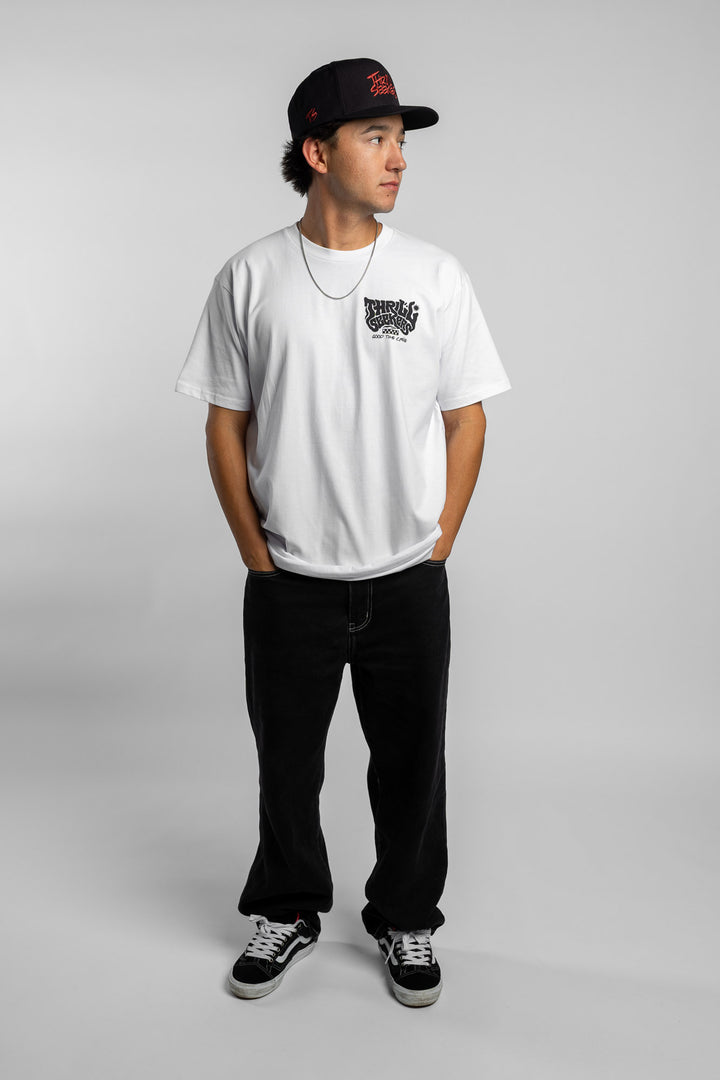 Person wearing a white t-shirt with black 'Thrill Seekers' smokin' logo