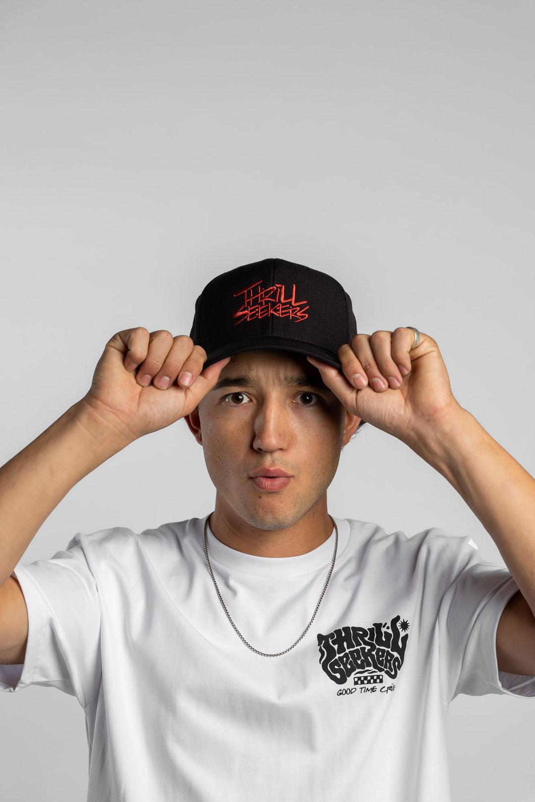 Person wearing a white t-shirt with black 'Thrill Seekers' smokin' logo