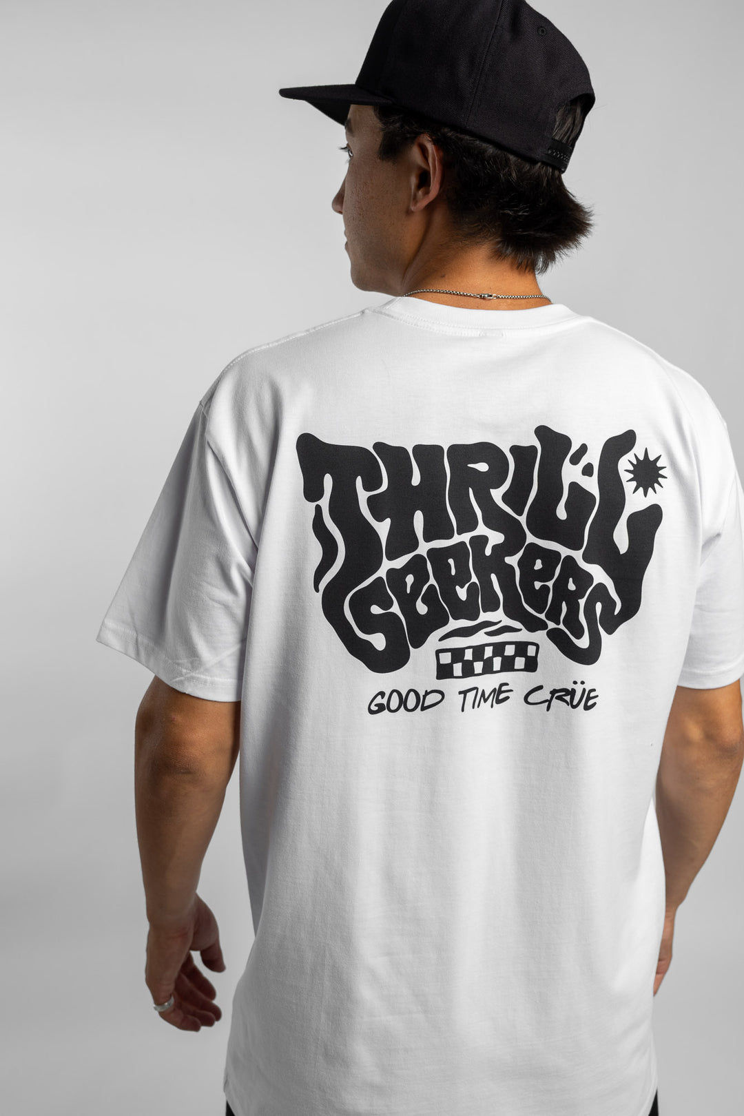 Person wearing a white t-shirt with black 'Thrill Seekers' smokin' logo