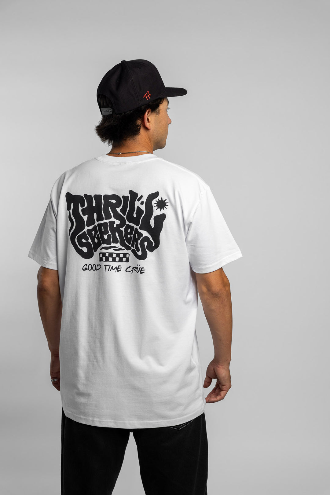 Person wearing a white t-shirt with black 'Thrill Seekers' smokin' logo