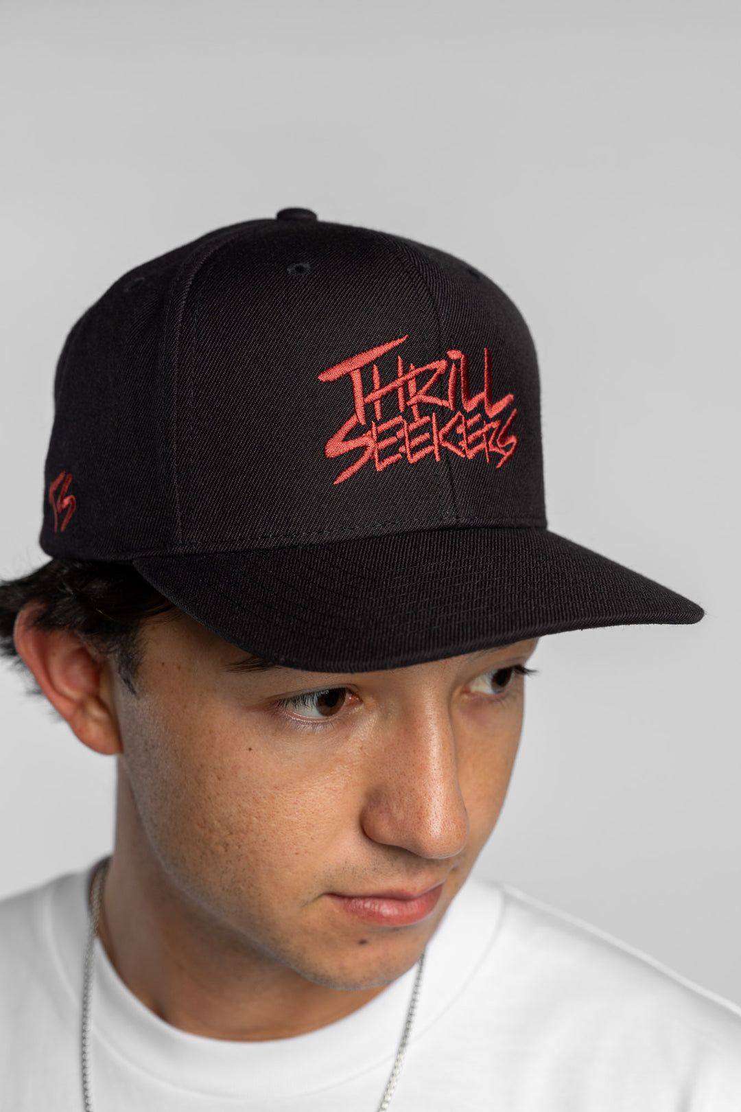 Person in black snapback hat with 'Thrill Seekers' logo in cardinal red