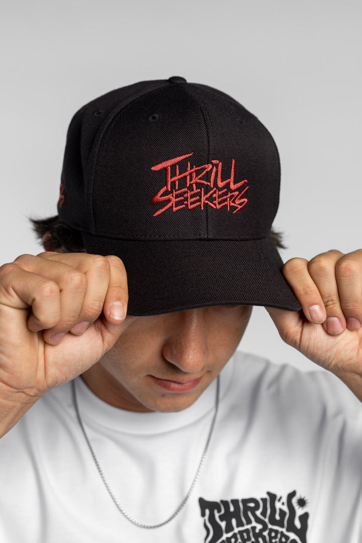 Person in black snapback hat with 'Thrill Seekers' logo in cardinal red