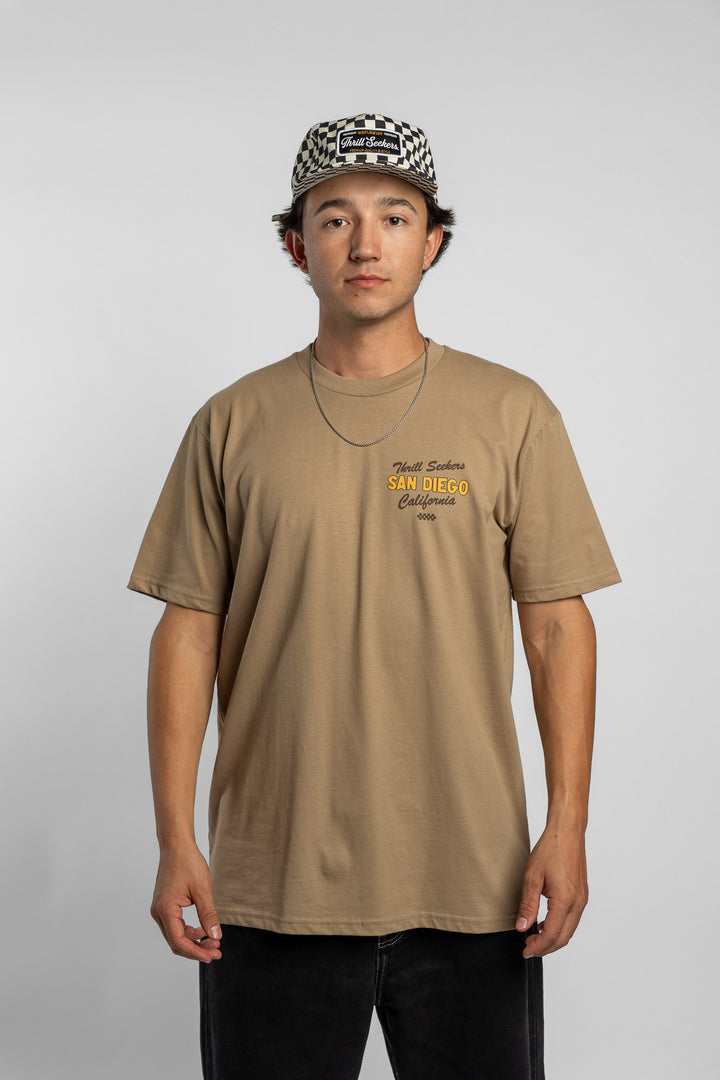 Person wearing sand tee with 'Thrill Seekers' shop logo