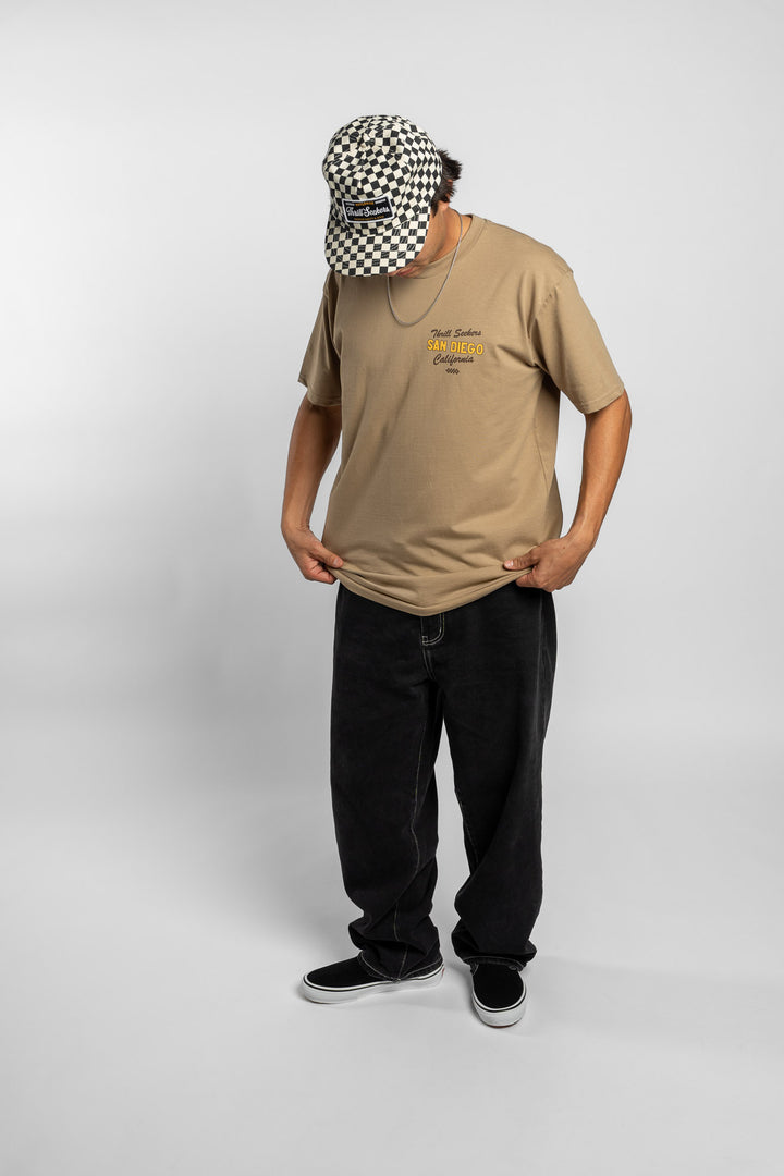 Person wearing sand tee with 'Thrill Seekers' shop logo