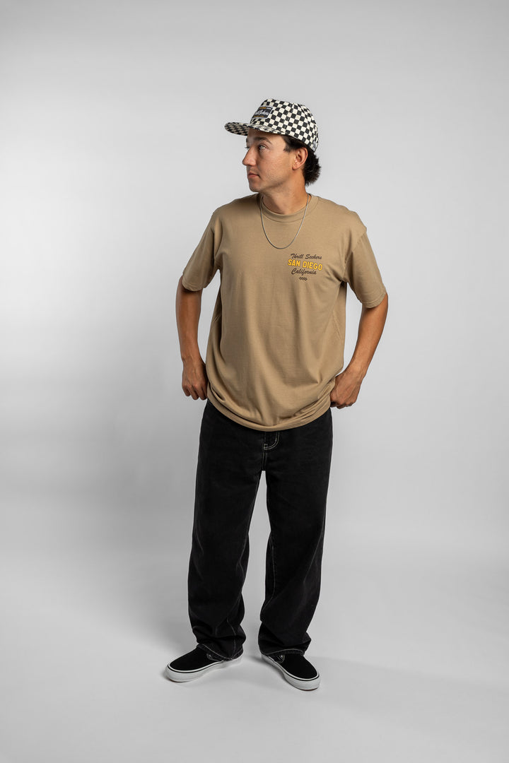 Person wearing sand tee with 'Thrill Seekers' shop logo