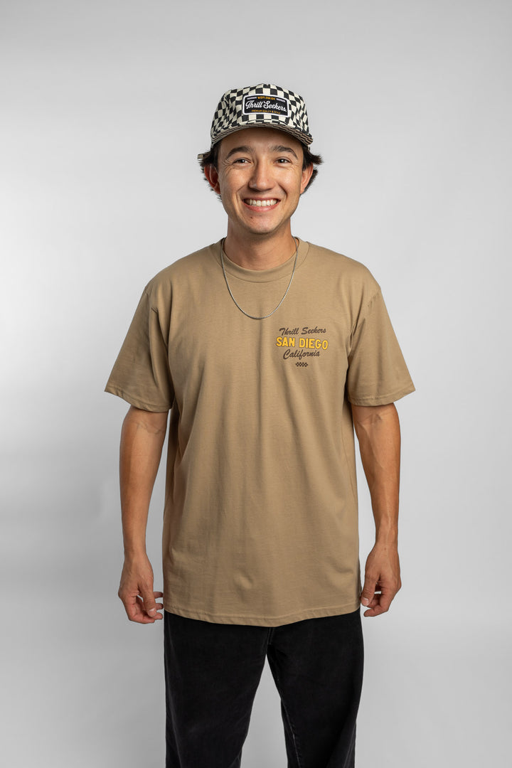 Person wearing sand tee with 'Thrill Seekers' shop logo