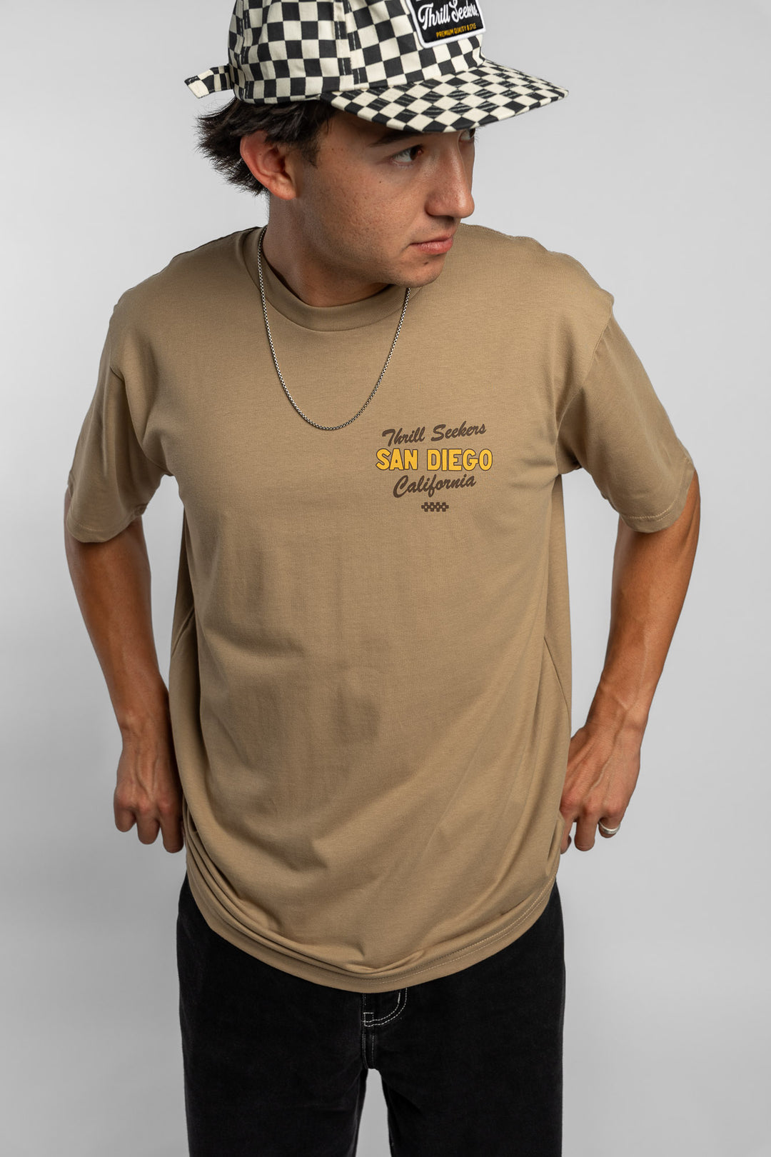 Person wearing sand tee with 'Thrill Seekers' shop logo