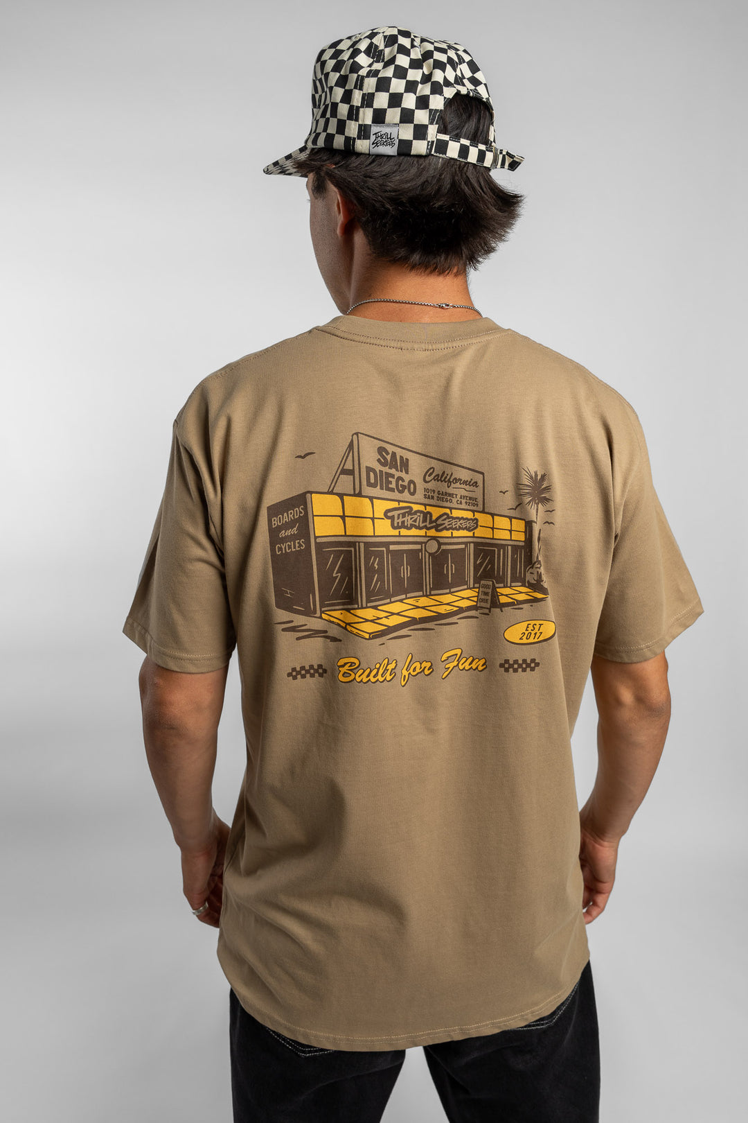 Person wearing sand tee with 'Thrill Seekers' shop logo