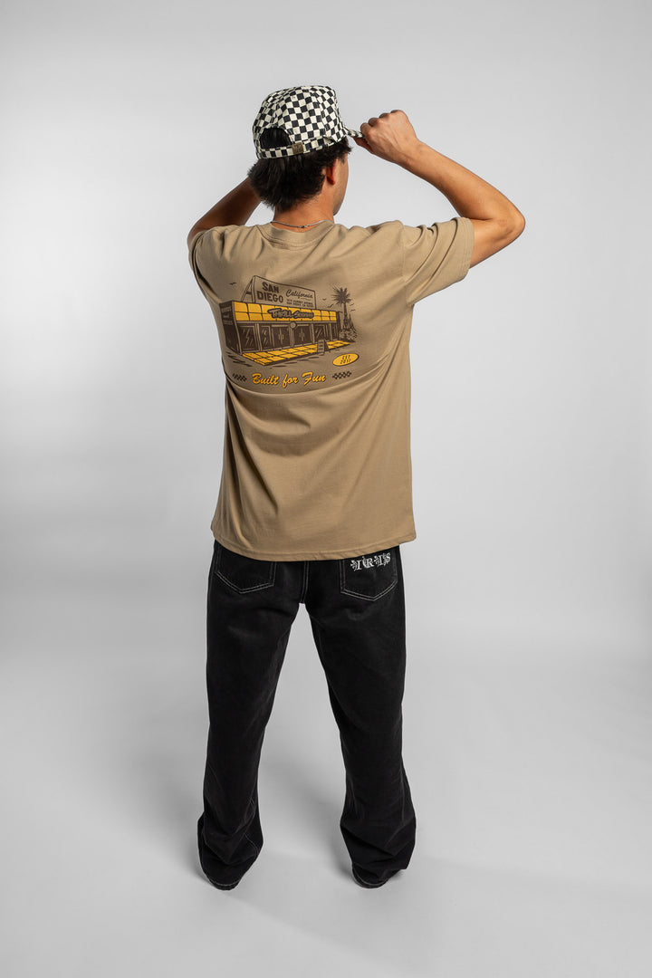 Person wearing sand tee with 'Thrill Seekers' shop logo