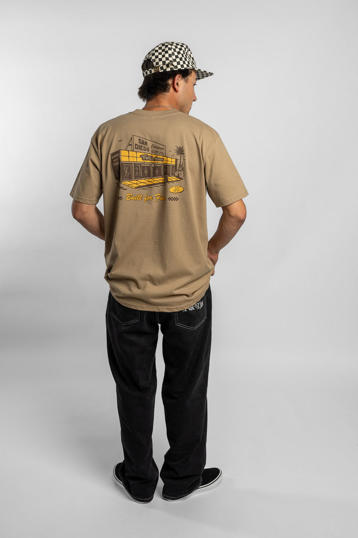Person wearing sand tee with 'Thrill Seekers' shop logo