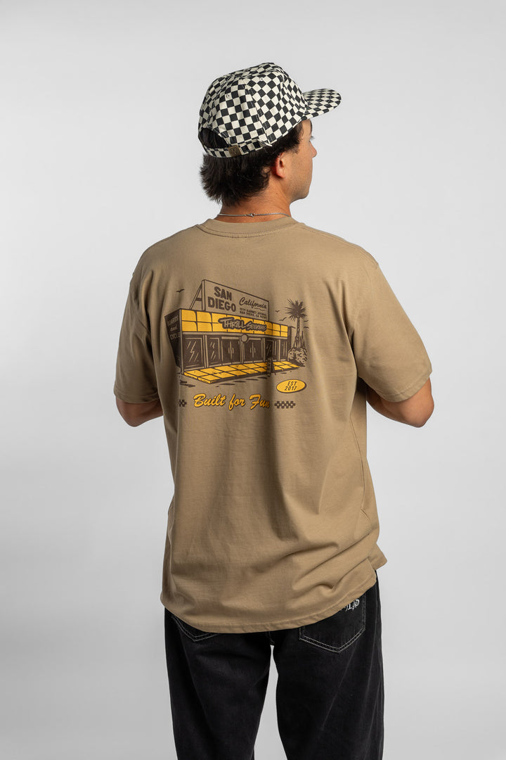 Person wearing sand tee with 'Thrill Seekers' shop logo