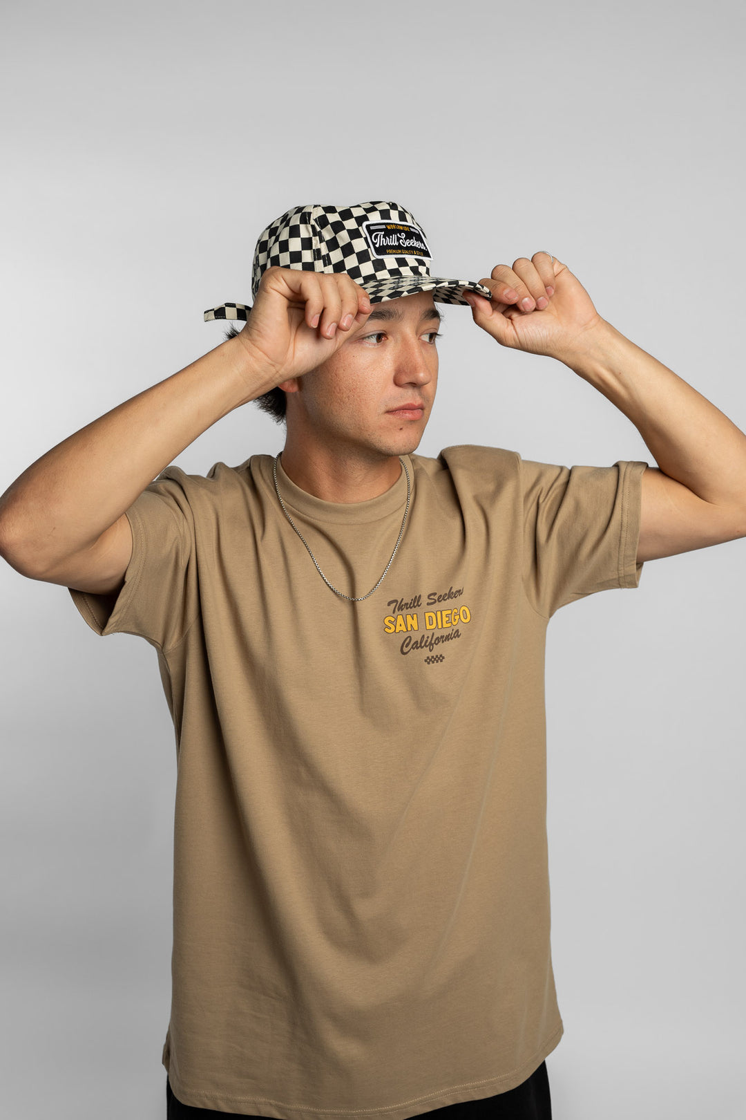 Person wearing a black checkered cap with a 'Thrill Seekers' logo
