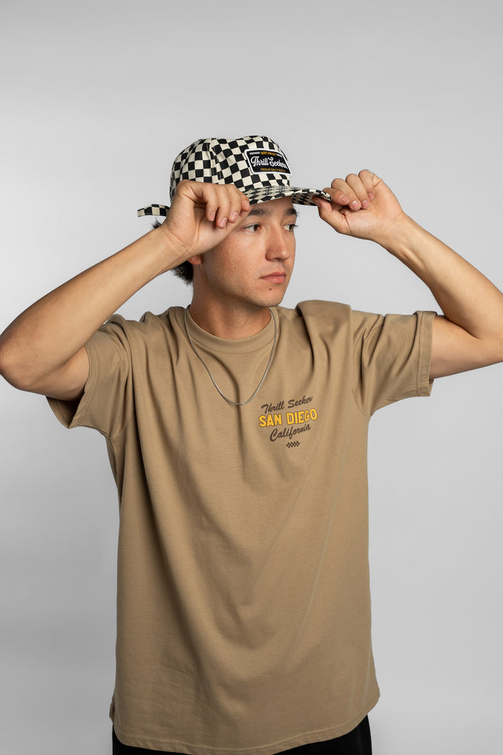 Person wearing a black checkered cap with a 'Thrill Seekers' logo