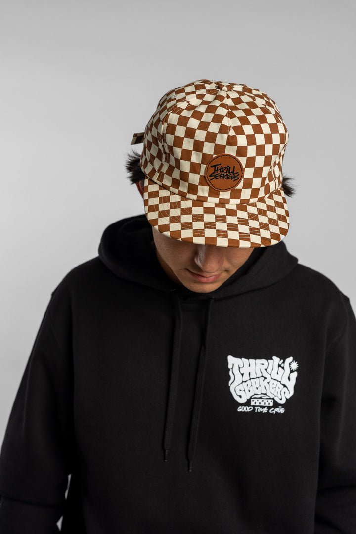 Person wearing rust checkered hat on white background