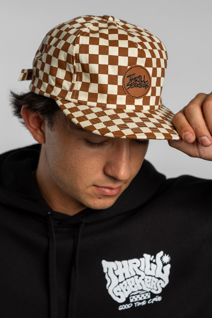 Person wearing rust checkered hat on white background