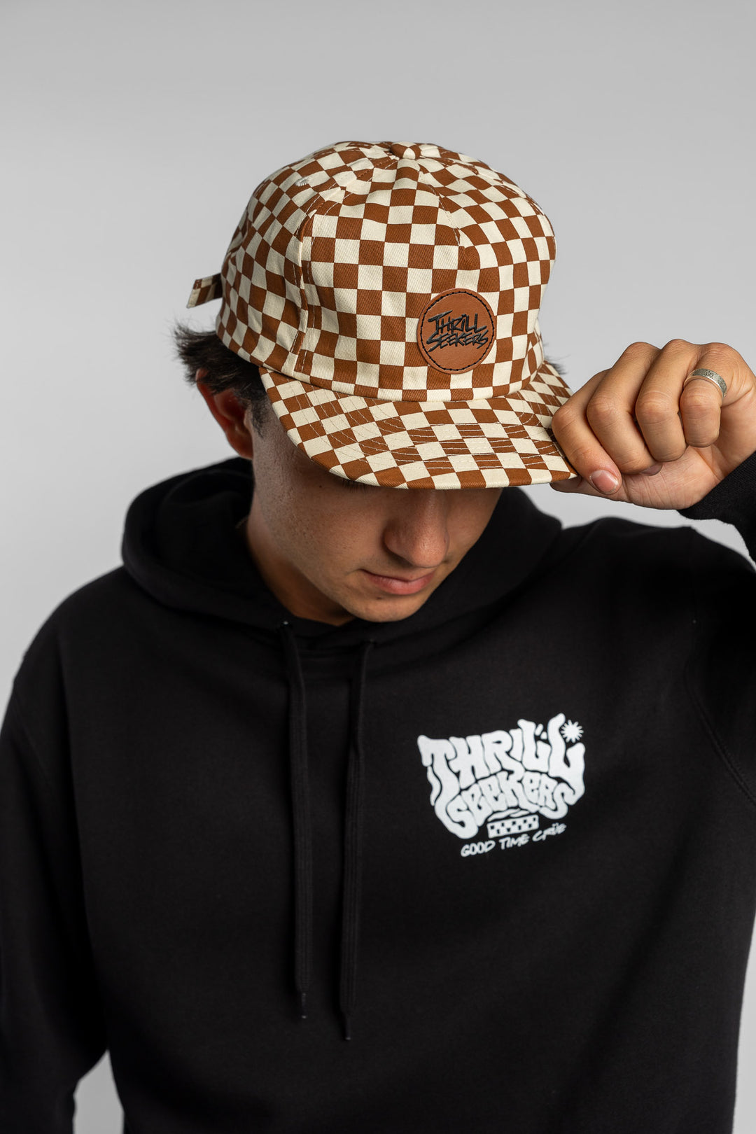 Person wearing rust checkered hat on white background