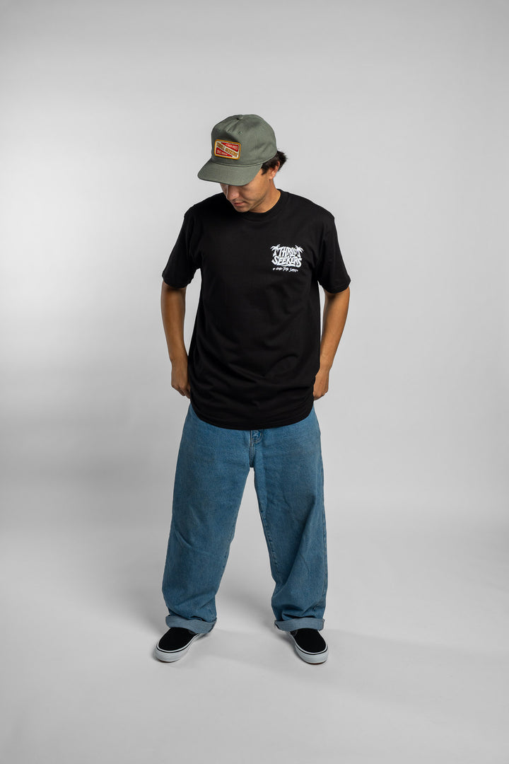 Person wearing black tee with 'Thrill Seekers' good time supply logo in white