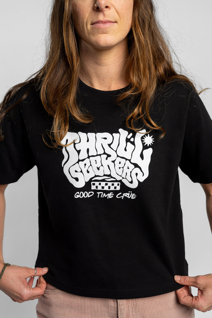 Woman wearing a black crop with 'Thrill Seekers' logo on a white background