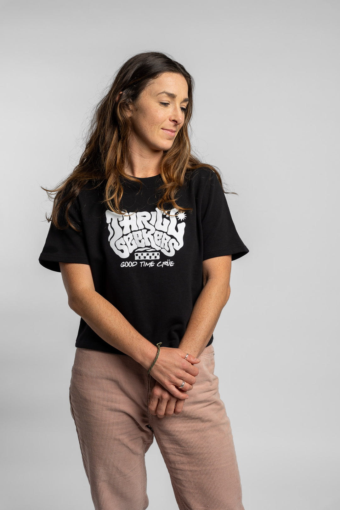 Woman wearing a black crop with 'Thrill Seekers' logo on a white background