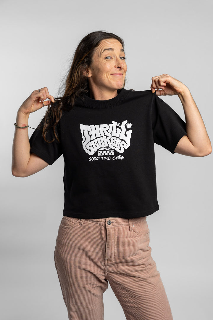Woman wearing a black crop with 'Thrill Seekers' logo on a white background
