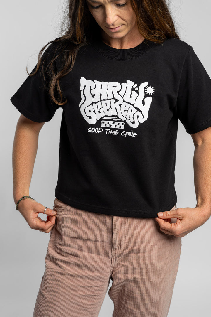 Woman wearing a black crop with 'Thrill Seekers' logo on a white background