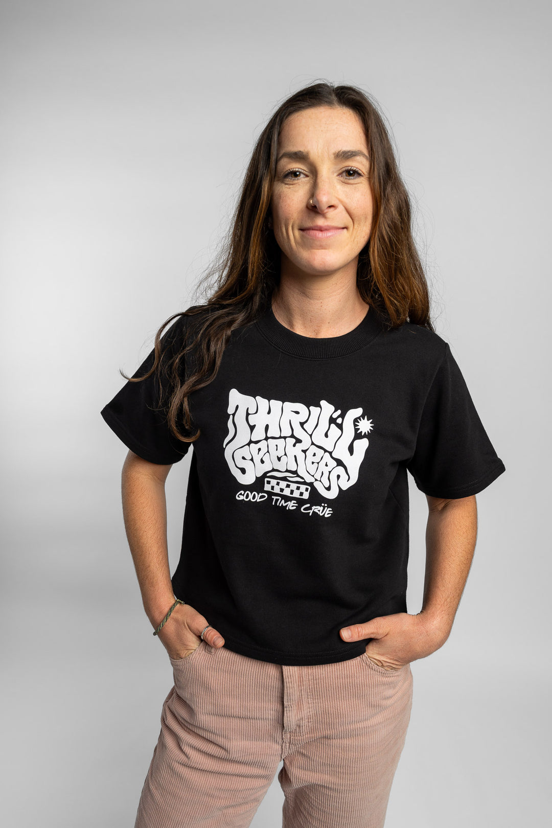 Woman wearing a black crop with 'Thrill Seekers' logo on a white background