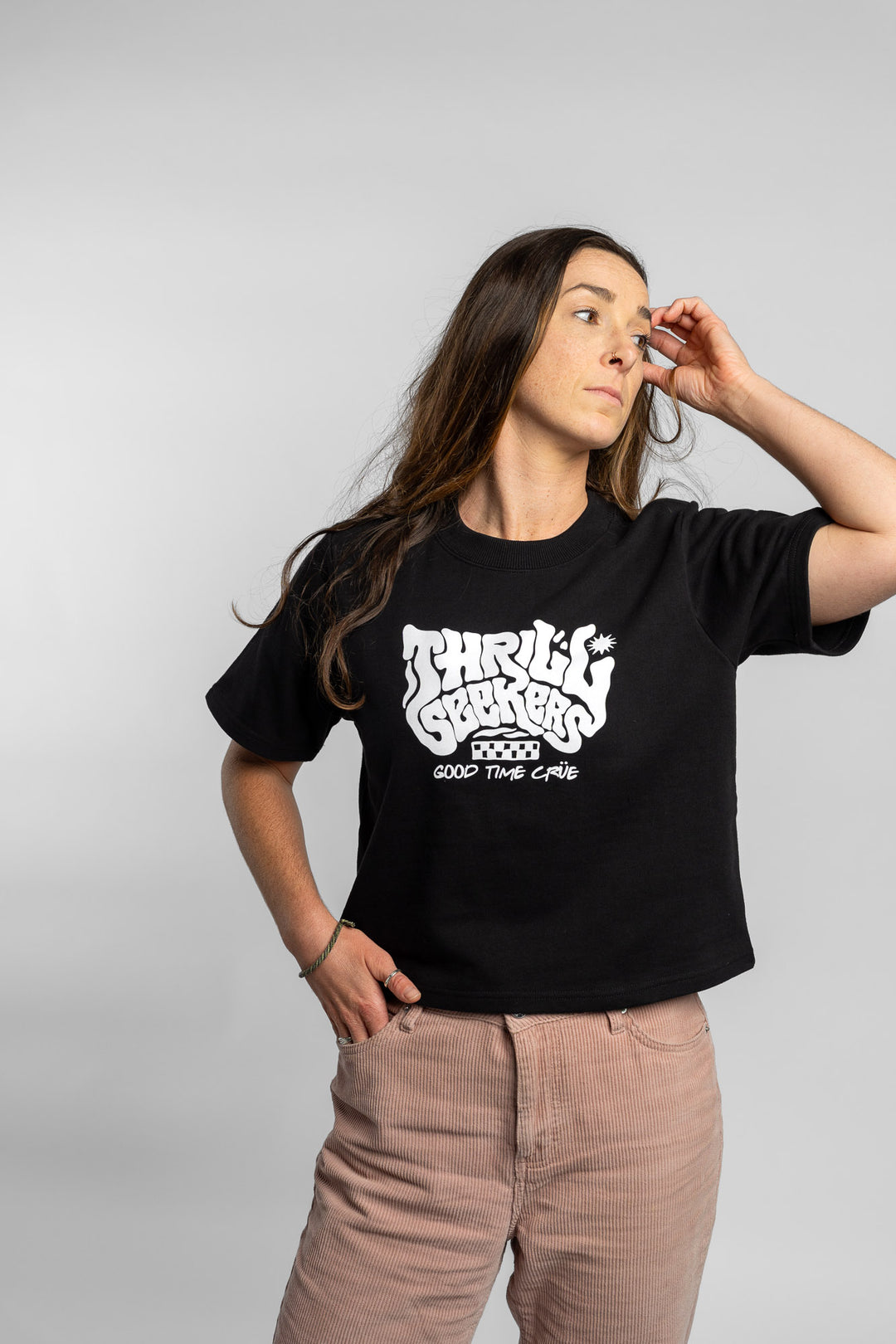 Woman wearing a black crop with 'Thrill Seekers' logo on a white background